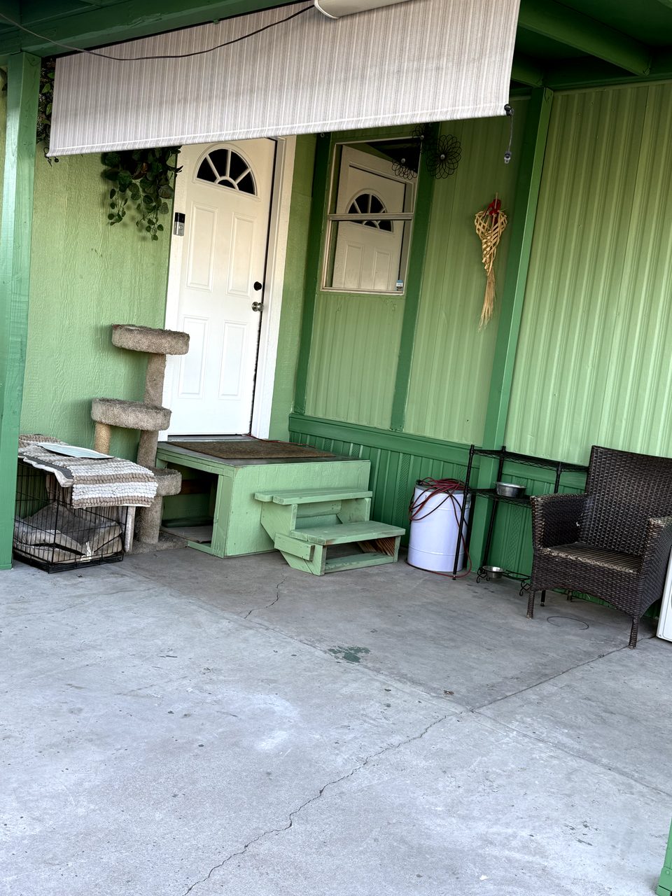 Finished covered porch entry on a Phoenix mobile home with deep green beams and a white door