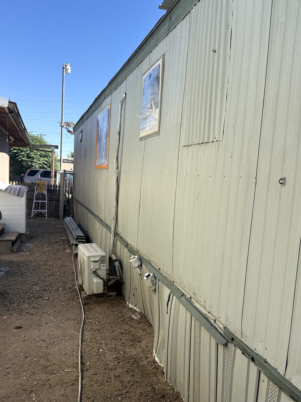 Faded chalky tan-gray metal siding on a Phoenix mobile home before painting