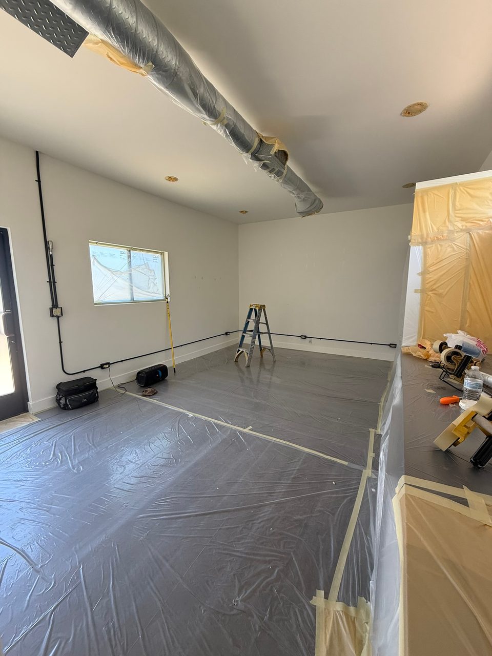 The room masked off, with the ceiling patched where recessed lights had been cut in